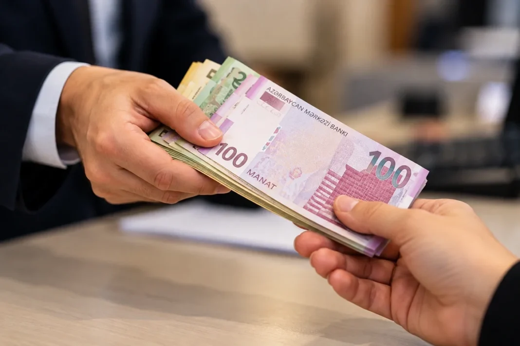Azerbaycan’da kredi yatırımları yüzde 14,5 artarak 34,9 milyar manata çıktı Masa üzerinde Azerbaycan manatı teslim eden kişi